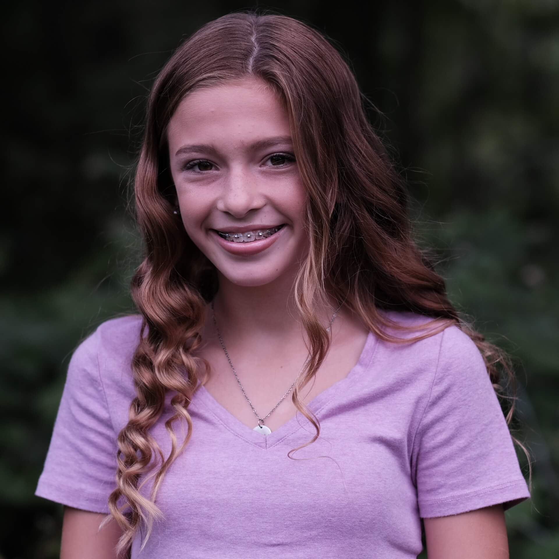 An image of a young girl in braces who is smiling