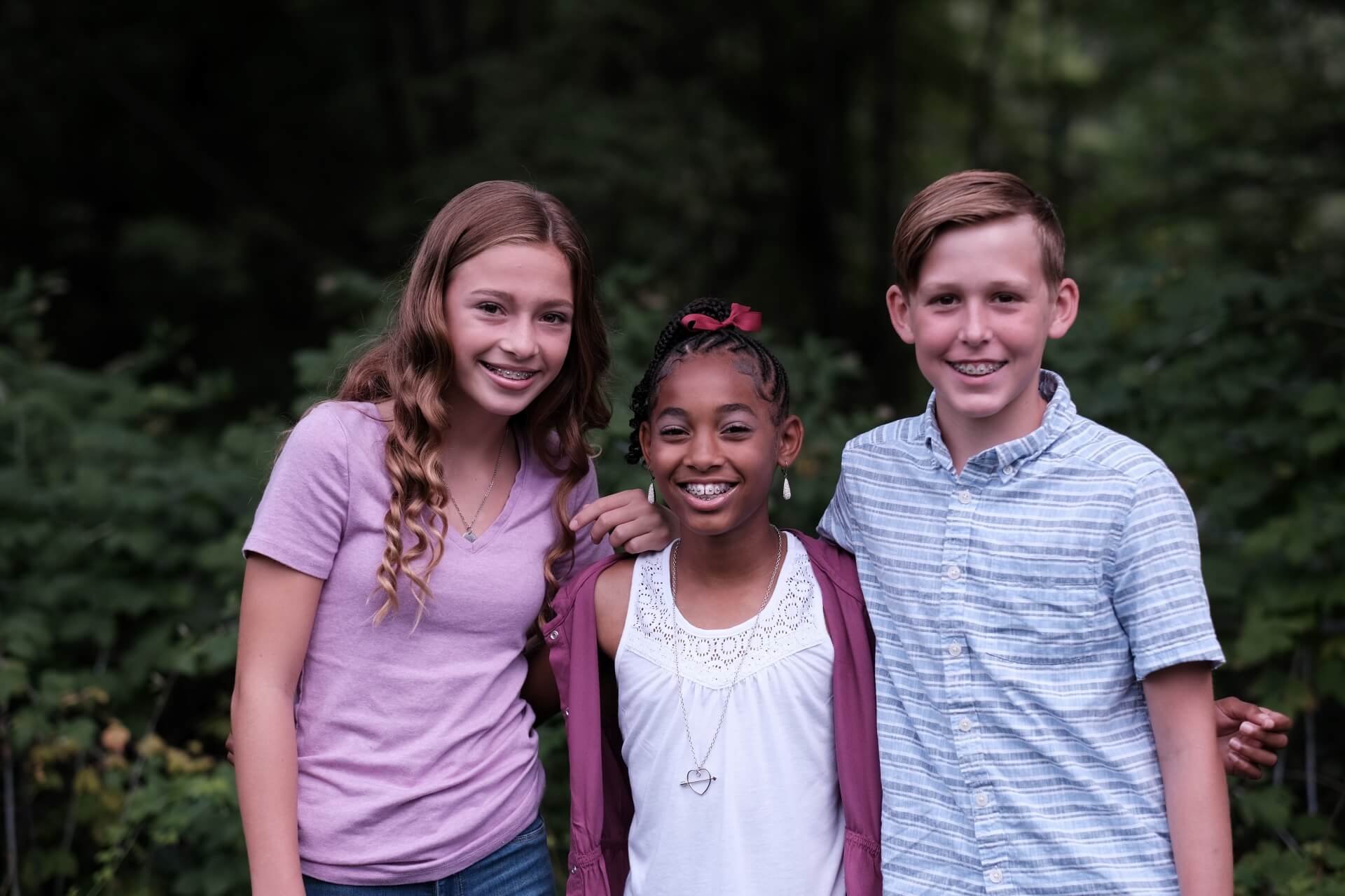 A photo of smiling boy and two girls