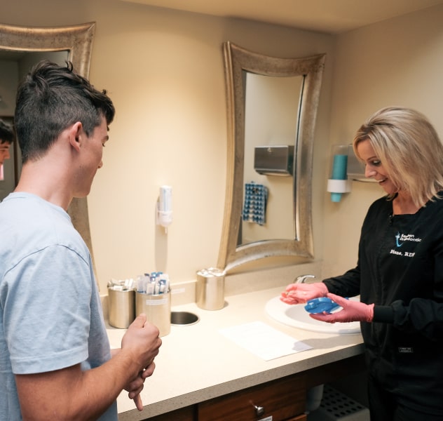 One of our dental assistants from Bandeen Orthodontics and Center for Dental Sleep Medicine showing clear aligners to a young man